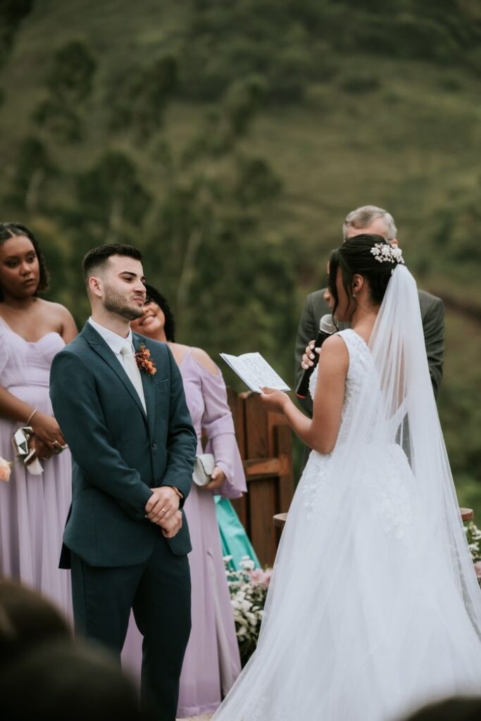 Bride and groom exchanging vows at outdoor wedding ceremony, surrounded by bridesmaids.
